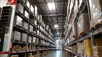 Wide aisle in large warehouse with stacked boxes on shelves