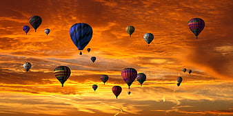 Colorful Hot Air Balloons Flying Against Dramatic Orange Sunset Sky