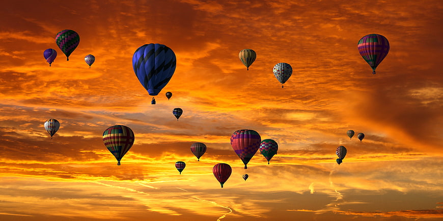 Colorful Hot Air Balloons Flying Against Dramatic Orange Sunset Sky