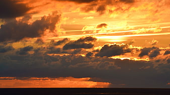 Dramatic Orange Sunset Sky Over Dark Ocean Horizon