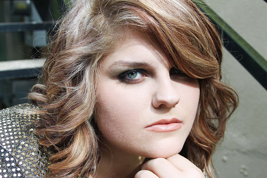 Close-up portrait of young woman with wavy hair and sparkly top