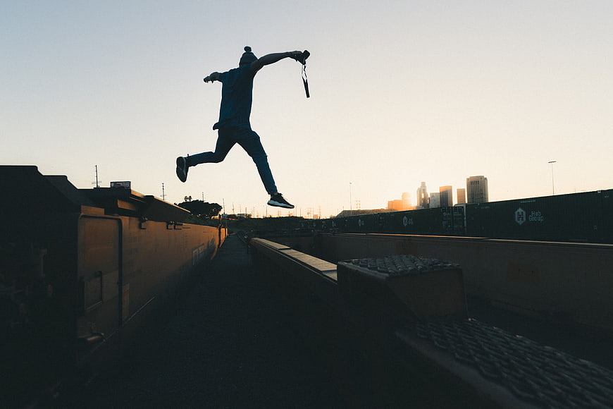 Silhouette of Man Jumping Between Train Cars at Sunset