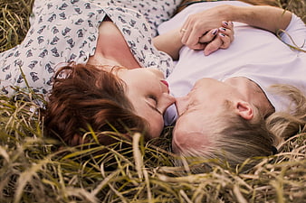 Romantic couple lying in grass holding hands