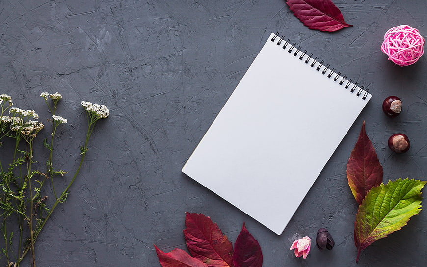 Autumn flat lay with blank notebook, leaves, and chestnuts on gray background