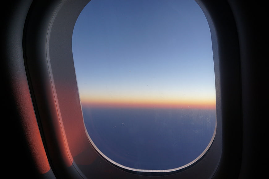 Airplane Window View of Sunrise Over Clouds
