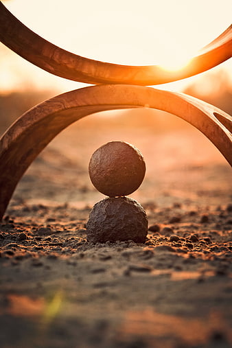 Balanced stones and wooden arch at golden hour sunset