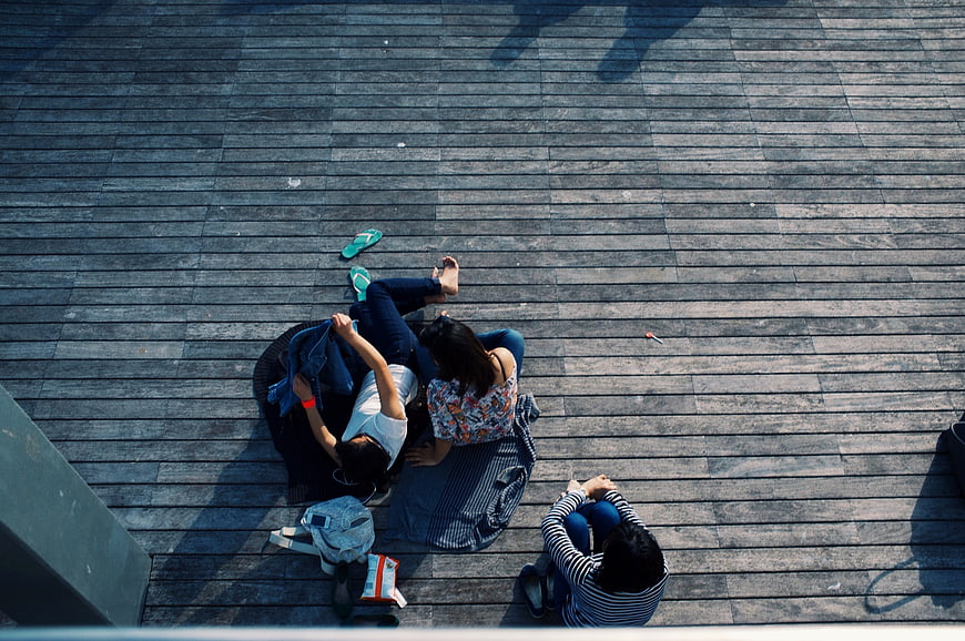 High angle view of three friends relaxing on wooden deck