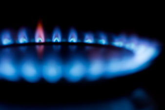 Close-up of blue gas stove burner flames on black background