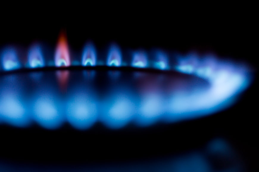 Close-up of blue gas stove burner flames on black background