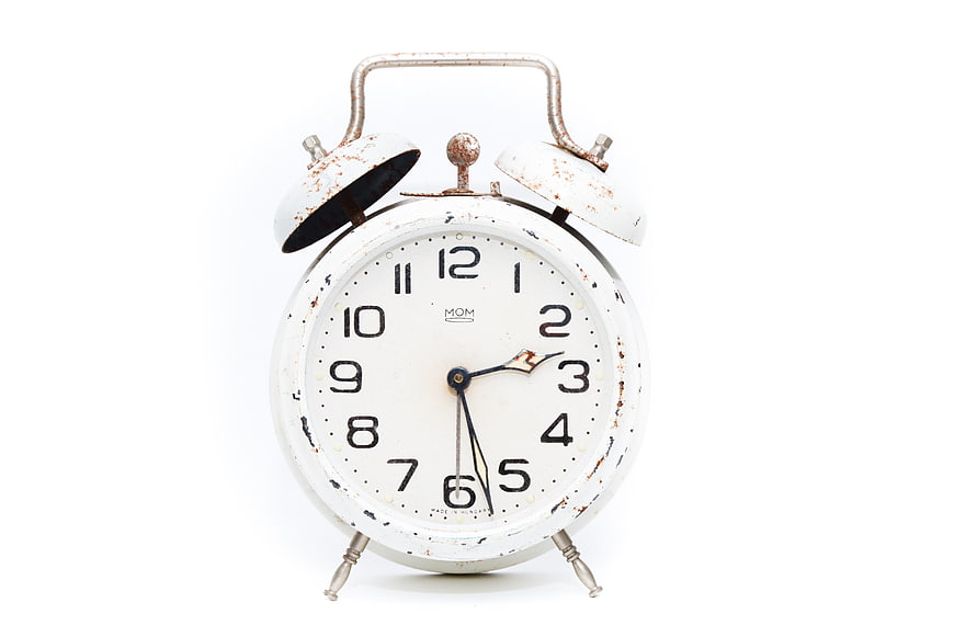 Vintage White Alarm Clock with Rust Details on White Background