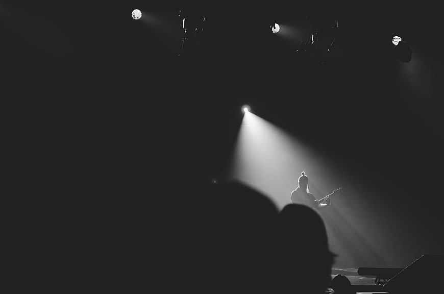 Silhouette of guitarist performing under spotlight on dark stage