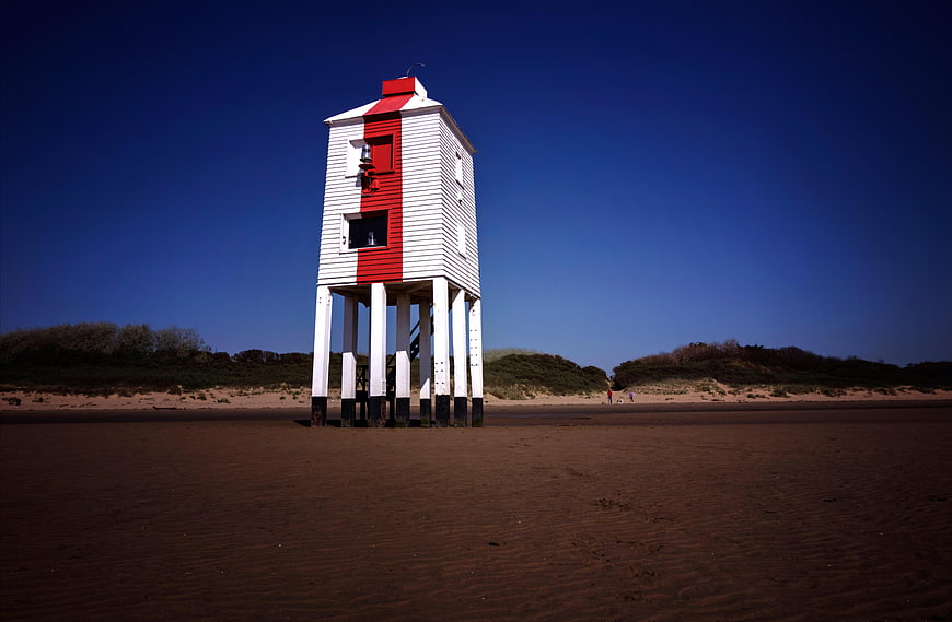 Red and white lifeguard tower on sandy beach
