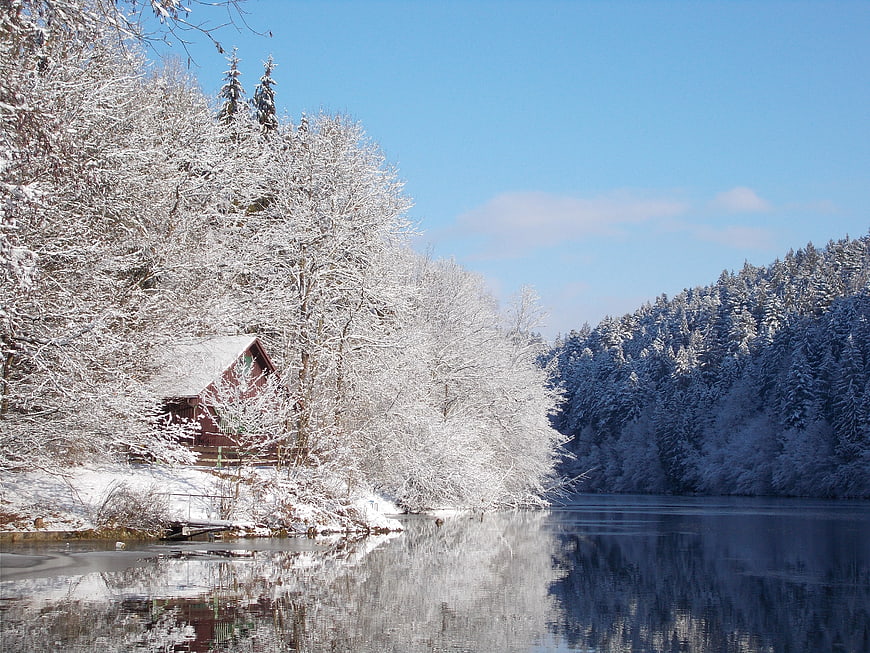 Serene Winter Lake Landscape with Snowy Cabin and Forest