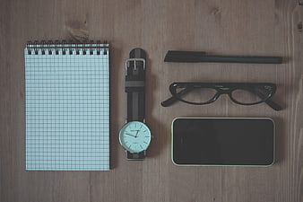 Flat lay of office supplies on wooden desk with notebook and smartphone