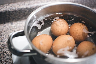 Brown eggs boiling in a stainless steel pot on a stove