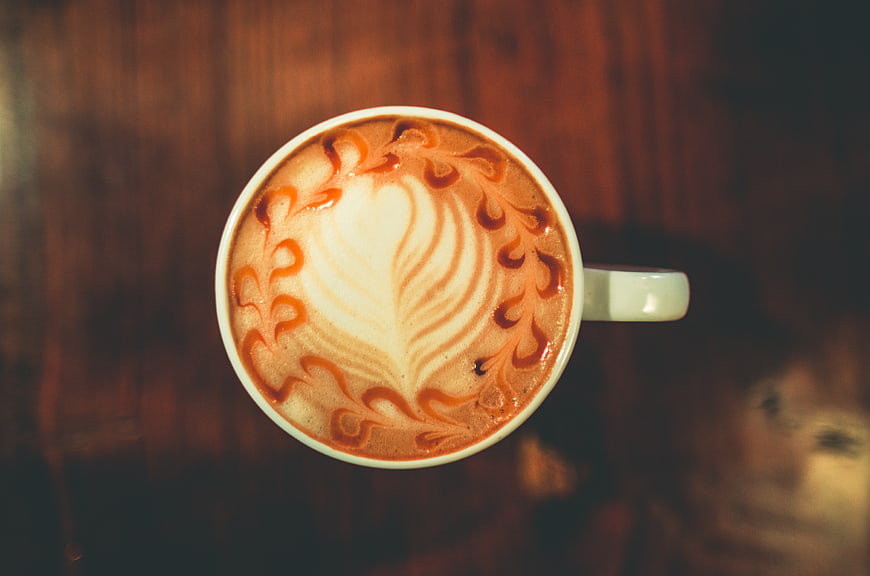 Top View of Cappuccino with Intricate Latte Art on Wooden Table