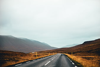 Empty asphalt road winding through misty autumn mountains