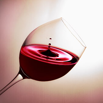 Red wine splash in glass with droplets