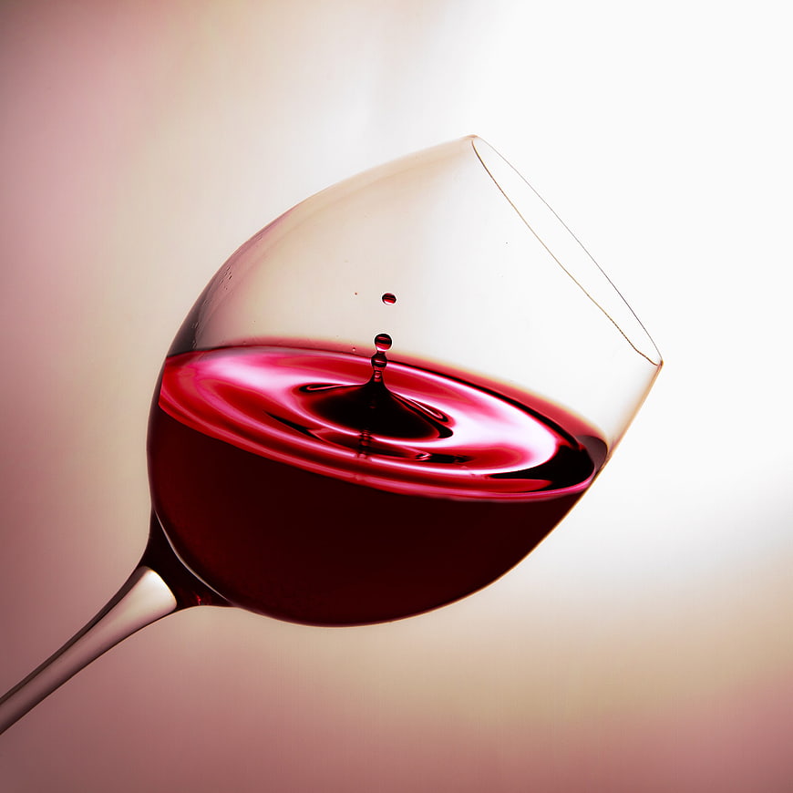 Red wine splash in glass with droplets