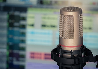 Gold condenser microphone with blurred audio editing software background