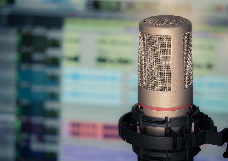 Gold condenser microphone with blurred audio editing software background