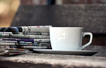 White Coffee Cup on Stack of Rolled Newspapers