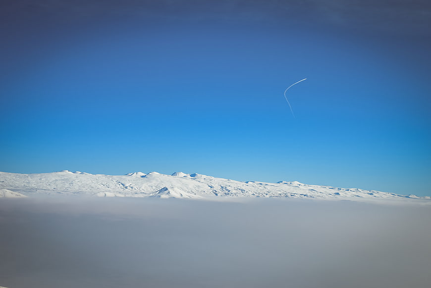 Snowy mountain peaks rising above clouds with blue sky