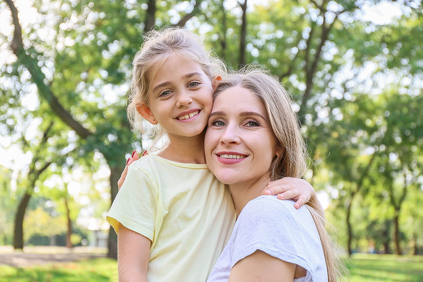 Happy mother and daughter hugging in a sunny park