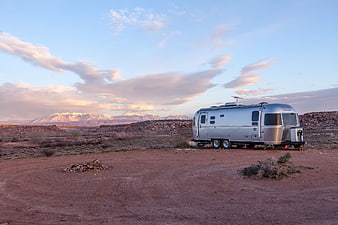 Silver Airstream Trailer in Desert Landscape with Mountains