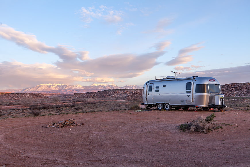Silver Airstream Trailer in Desert Landscape with Mountains