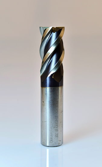 Close-up of a metal end mill cutter with spiral flutes on a white background