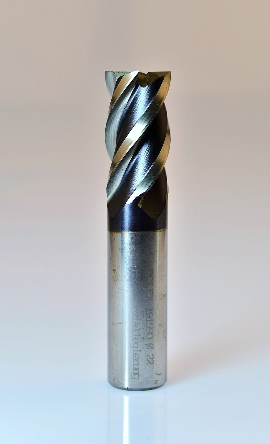 Close-up of a metal end mill cutter with spiral flutes on a white background
