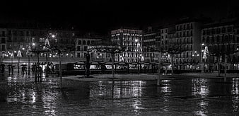 Black and white night view of wet city square with reflections