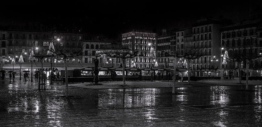 Black and white night view of wet city square with reflections