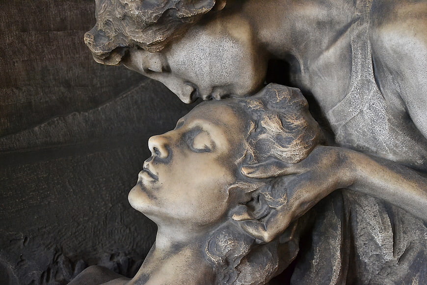 Close-up of stone sculpture depicting a tender kiss between two figures