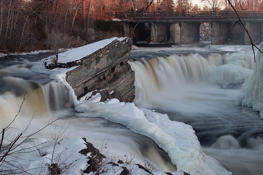 Winter waterfall with ice formations and bridge