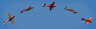 Five Orange RC Airplanes Flying in Formation Against Blue Sky