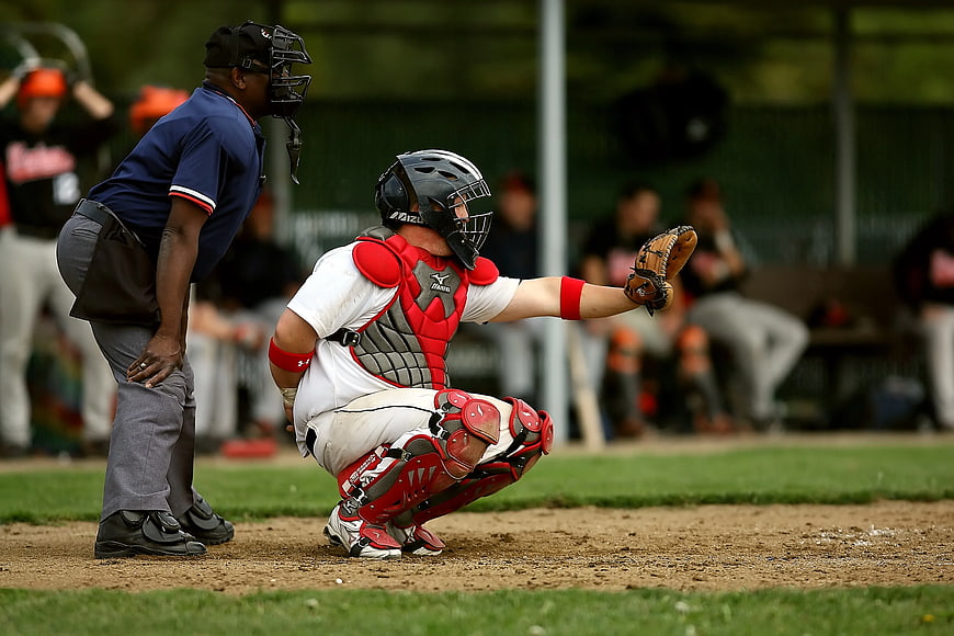 Baseball Catcher in Red Gear Receiving Pitch