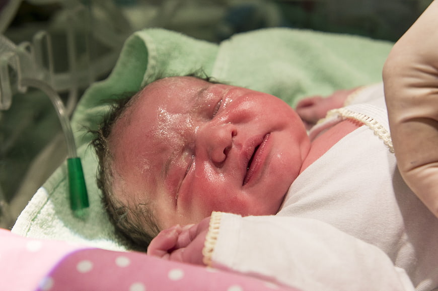 Newborn Baby Sleeping In Hospital Bed With Medical Equipment
