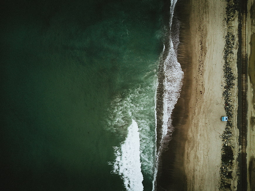 Aerial View of Ocean Waves Crashing on Sandy Beach