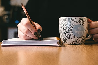Woman Writing in Notebook with Be Happy Coffee Mug