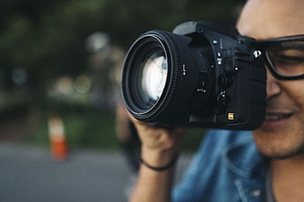 Close-up of photographer holding camera with lens