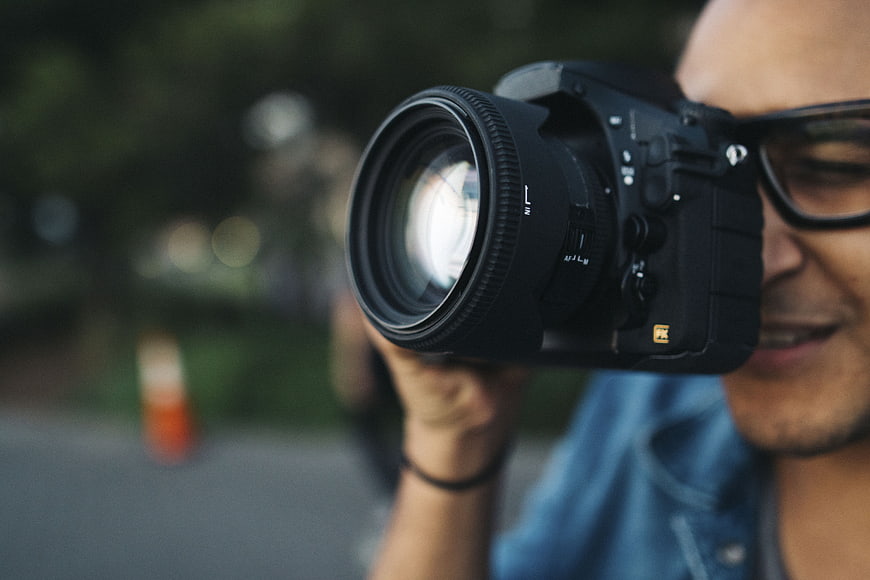 Close-up of photographer holding camera with lens