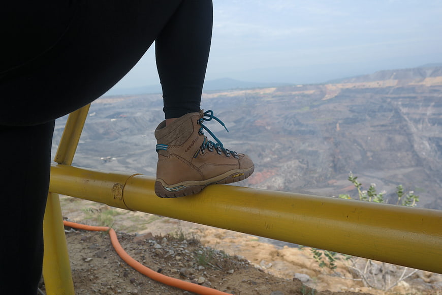 Hiker boot on yellow railing overlooking open pit mine