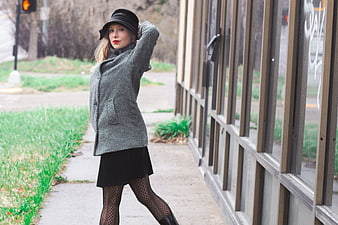 Stylish woman in vintage coat and hat posing on city sidewalk