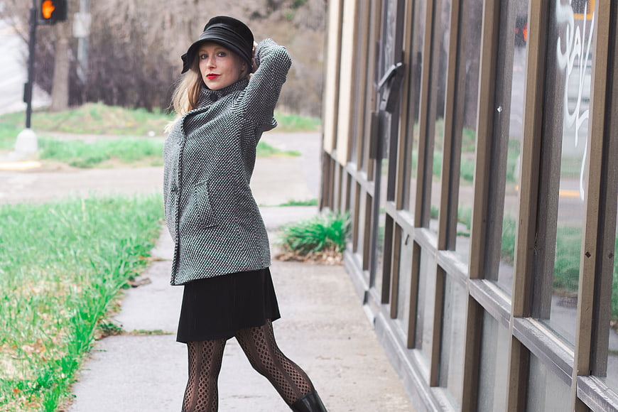 Stylish woman in vintage coat and hat posing on city sidewalk