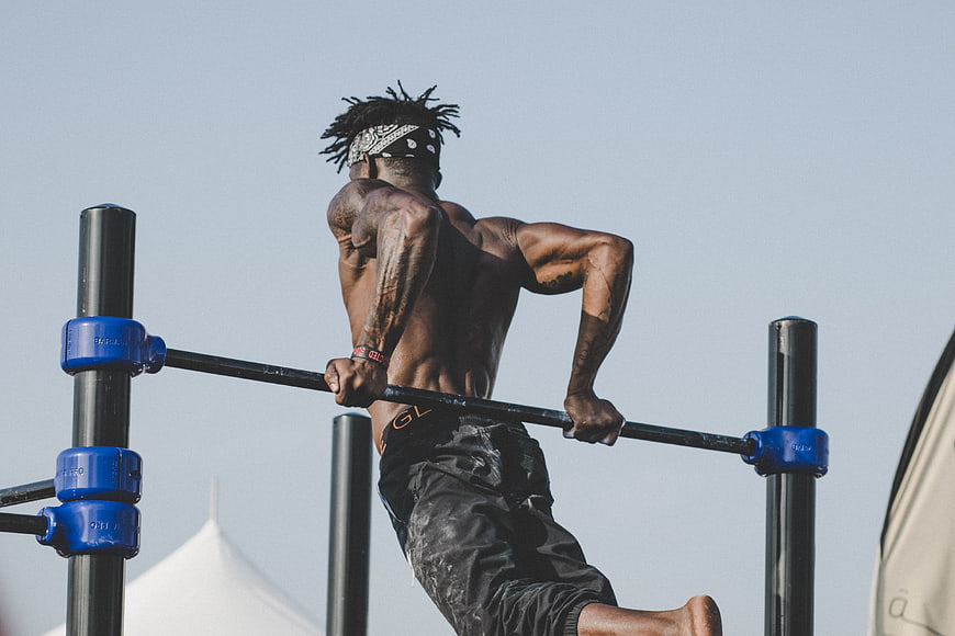 Muscular Man Doing Muscle-Up on Outdoor Pull-Up Bar