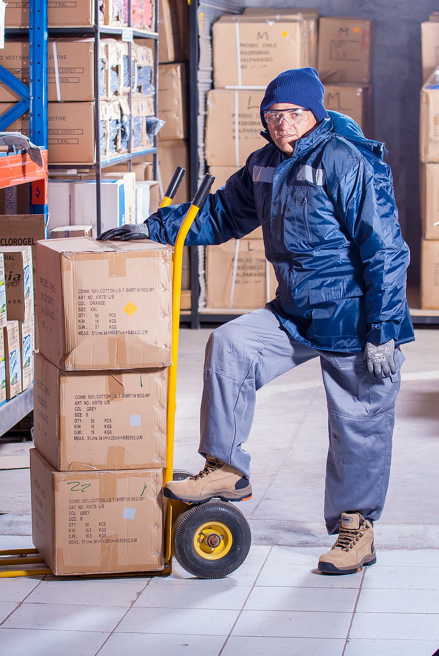 Warehouse worker with hand truck and boxes