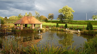 Serene Park Pond with Gazebo and Fountain Under Dramatic Sky