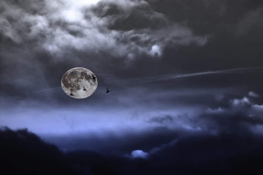 Full moon with bats flying through dramatic cloudy night sky